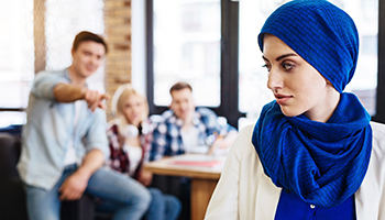 Group of students humiliating young muslim woman