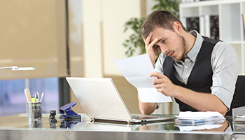 Sad businessman reading bad news in a letter sitting in a desk at office